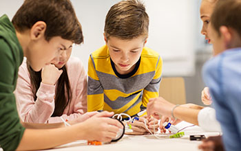 Children building robots around a table